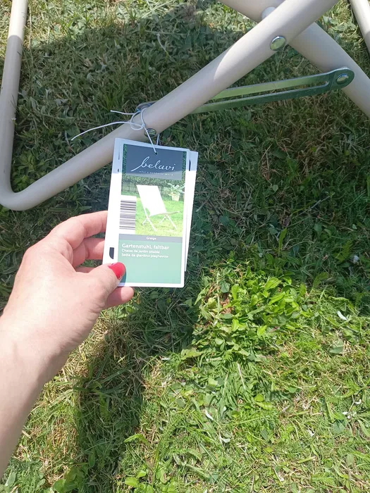Trzyczęściowy zestaw mebli ogrodowych dwa białe leżaki i okrągły stolik na trawniku