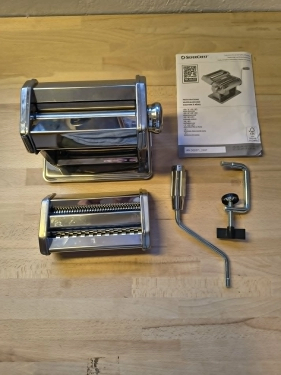 Biały karton z maszynką do makaronu Silvercrest Pasta Machine na drewnianym blacie