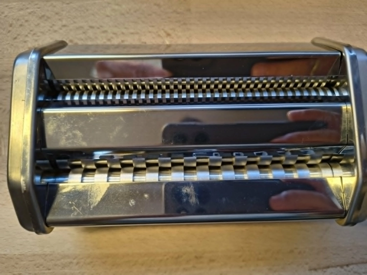 Biały karton z maszynką do makaronu Silvercrest Pasta Machine na drewnianym blacie