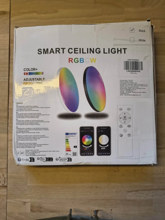 Czarna inteligentna lampa sufitowa LED plafon Smart Wi-Fi obok pilota i uszkodzonego kartonu