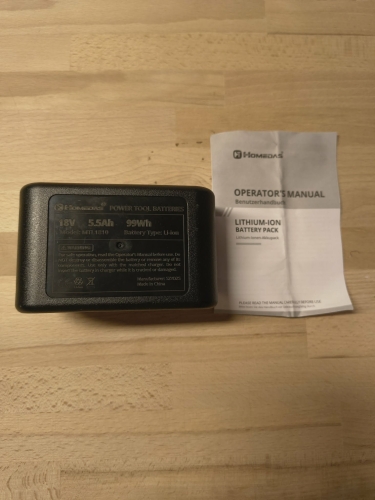 Czarny akumulator Homedas 18V 5.5Ah obok papierowej instrukcji obsługi