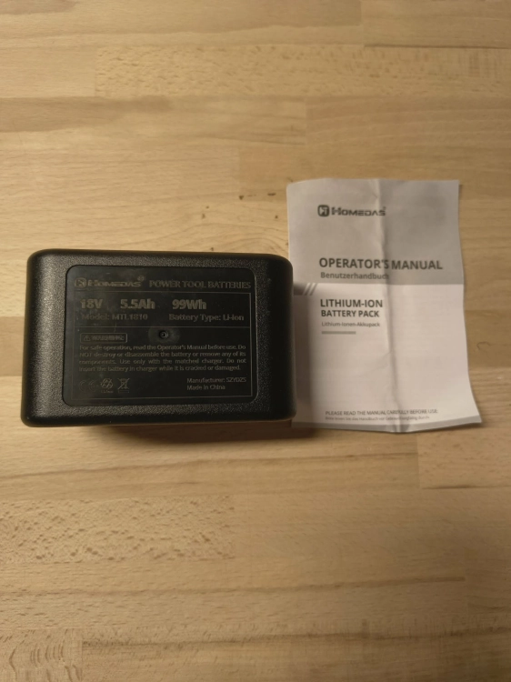 Czarny akumulator Homedas 18V 5.5Ah obok papierowej instrukcji obsługi