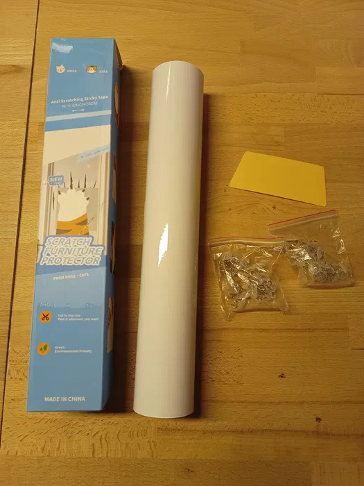Nowa przezroczysta rolka folii ochronnej przeciw drapaniu mebli przez kota i psa o szerokości 30 cm na tle boku kanapy