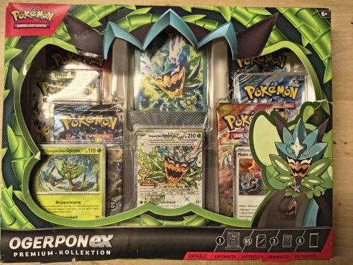 Nowy fabrycznie zamknięty zestaw Pokémon TCG Ogerpon ex Premium-Kollektion w niemieckiej wersji językowej z widocznymi boosterami i kartami promocyjnymi
