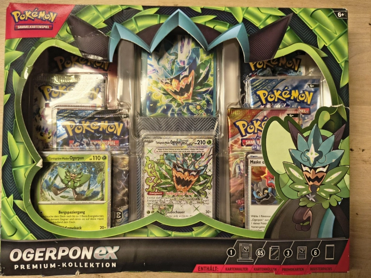 Nowy fabrycznie zamknięty zestaw Pokémon TCG Ogerpon ex Premium-Kollektion w niemieckiej wersji językowej z widocznymi boosterami i kartami promocyjnymi