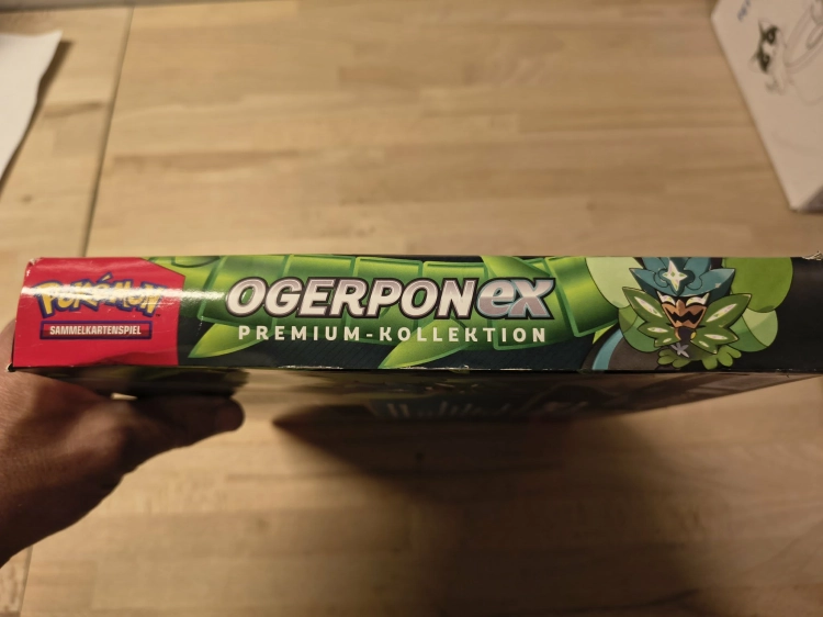 Nowy fabrycznie zamknięty zestaw Pokémon TCG Ogerpon ex Premium-Kollektion w niemieckiej wersji językowej z widocznymi boosterami i kartami promocyjnymi