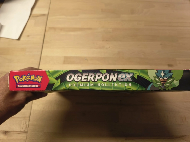 Nowy fabrycznie zamknięty zestaw Pokémon TCG Ogerpon ex Premium-Kollektion w niemieckiej wersji językowej z widocznymi boosterami i kartami promocyjnymi