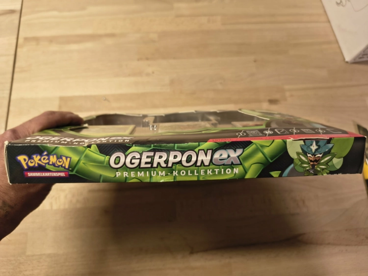 Nowy fabrycznie zamknięty zestaw Pokémon TCG Ogerpon ex Premium-Kollektion w niemieckiej wersji językowej z widocznymi boosterami i kartami promocyjnymi
