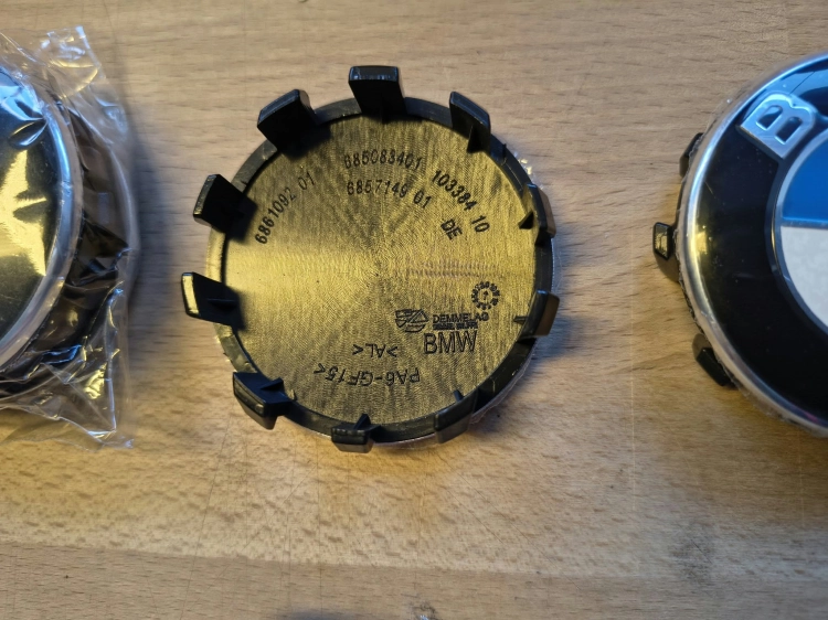 Nowe oryginalne dekielki kapselki do felg aluminiowych BMW o średnicy 56 mm z widocznymi numerami seryjnymi 6857149 na wewnętrznej stronie