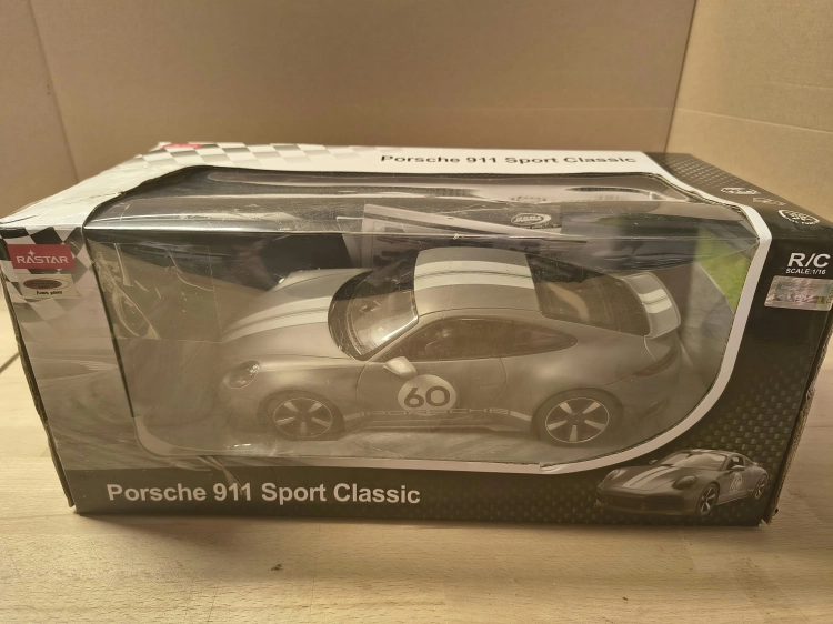 Nowe fabrycznie zapakowane szare zdalnie sterowane auto Porsche Sport Classic marki Rastar w skali 1 do 16 z widocznymi wgnieceniami na pudełku
