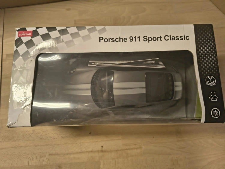 Nowe fabrycznie zapakowane szare zdalnie sterowane auto Porsche Sport Classic marki Rastar w skali 1 do 16 z widocznymi wgnieceniami na pudełku