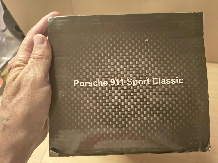 Nowe fabrycznie zapakowane szare zdalnie sterowane auto Porsche Sport Classic marki Rastar w skali 1 do 16 z widocznymi wgnieceniami na pudełku