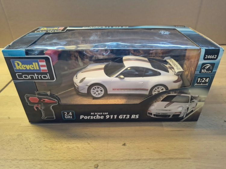 Nowe oryginalnie zapakowane białe zdalnie sterowane auto wyścigowe Revell Control Porsche 911 GT3 RS w skali 1 do 24 z widocznymi wgnieceniami na pudełku