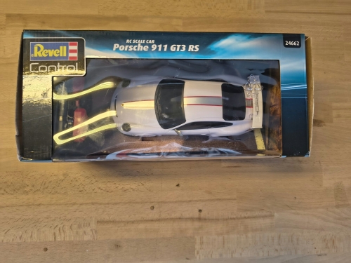 Nowe oryginalnie zapakowane białe zdalnie sterowane auto wyścigowe Revell Control Porsche 911 GT3 RS w skali 1 do 24 z widocznymi wgnieceniami na pudełku