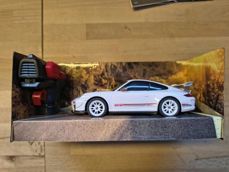 Nowe oryginalnie zapakowane białe zdalnie sterowane auto wyścigowe Revell Control Porsche 911 GT3 RS w skali 1 do 24 z widocznymi wgnieceniami na pudełku