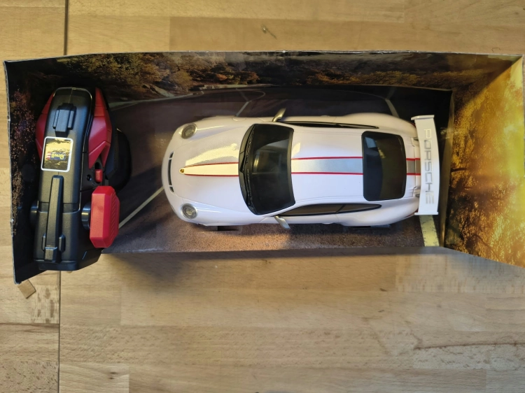 Nowe oryginalnie zapakowane białe zdalnie sterowane auto wyścigowe Revell Control Porsche 911 GT3 RS w skali 1 do 24 z widocznymi wgnieceniami na pudełku