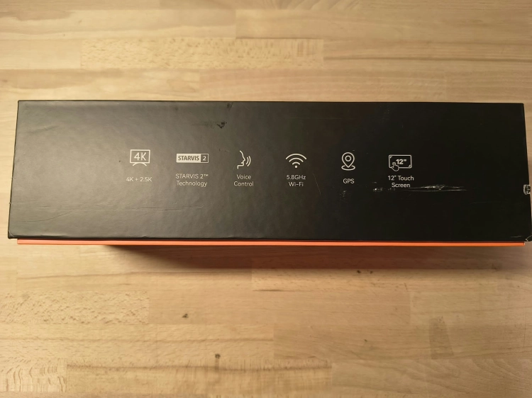 Nowy czarny wideorejestrator w lusterku WOLFBOX G900 Pro 4K rozpakowany z kompletem akcesoriów anteną GPS instrukcją i okablowaniem na drewnianym blacie