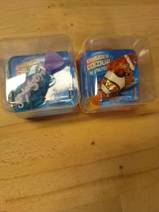Zestaw dwóch nowych interaktywnych rybek z serii Zuru Robo Alive Robo Fish w kolorze turkusowym i pomarańczowym w przezroczystych opakowaniach oraz po wyjęciu z pudełka